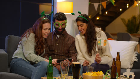 Group-Of-Friends-Dressing-Up-At-Home-Or-In-Bar-Celebrating-At-St-Patrick's-Day-Party-Looking-At-Photos-On-Phone-3